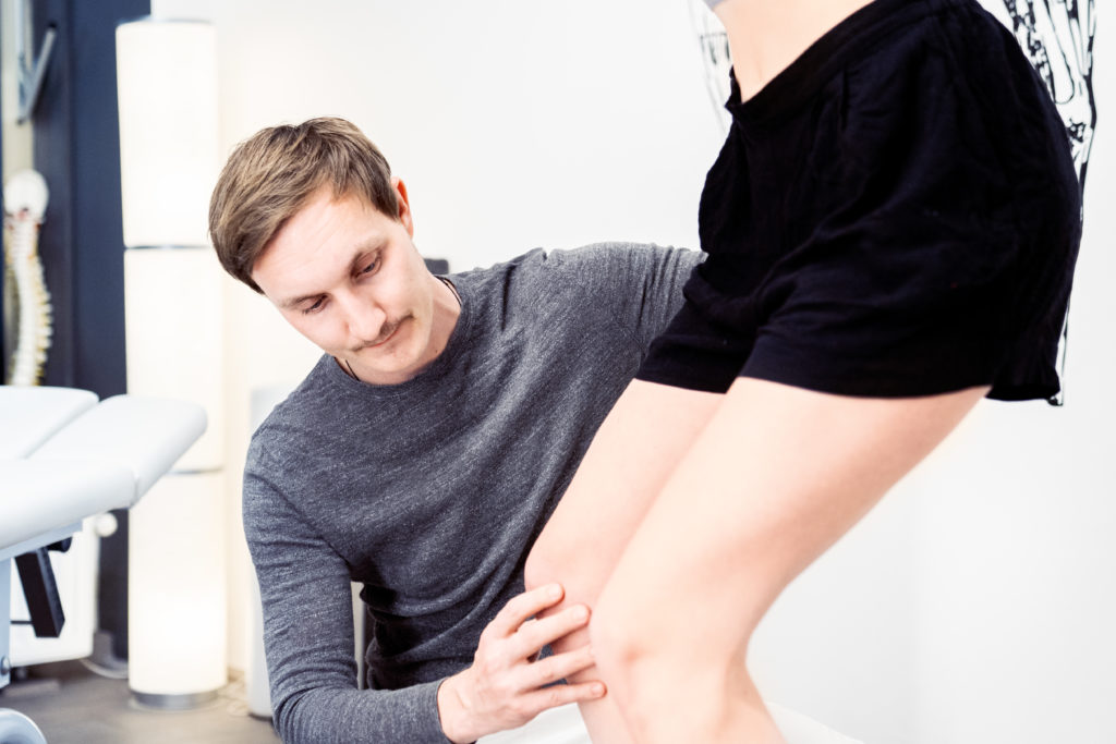 Philipp Schulz führt eine Behandlung in die Physiotherapie Wien mit einer Patientin am Knie durch.